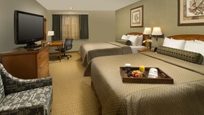 A hotel room with two beds, a desk with a chair, a television, and a tray with breakfast items. - Redmond Inn (Redmond)