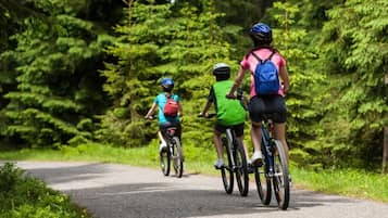 Three cyclists on a paved path surrounded by dense green foliage.