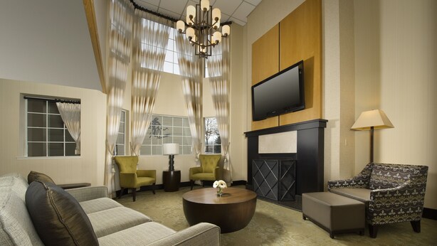 A modern living room with a sofa, armchairs, a coffee table, a fireplace, and a TV mounted on the wall. - Redmond Inn (Redmond)