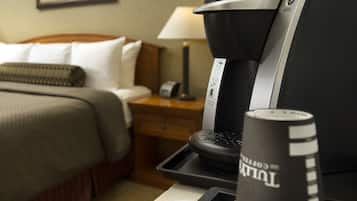 A hotel room with a bed, a nightstand with a lamp, and a coffee maker on a tray.