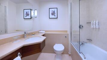 A modern bathroom with a large mirror, two sinks, a toilet, and a bathtub.