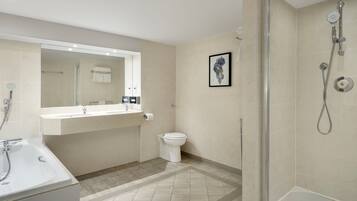 Un baño moderno con un espejo grande, un lavabo, un inodoro y una zona de ducha.