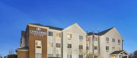 Un hotel Candlewood Suites con fachada de ladrillo, varias ventanas y un estacionamiento.