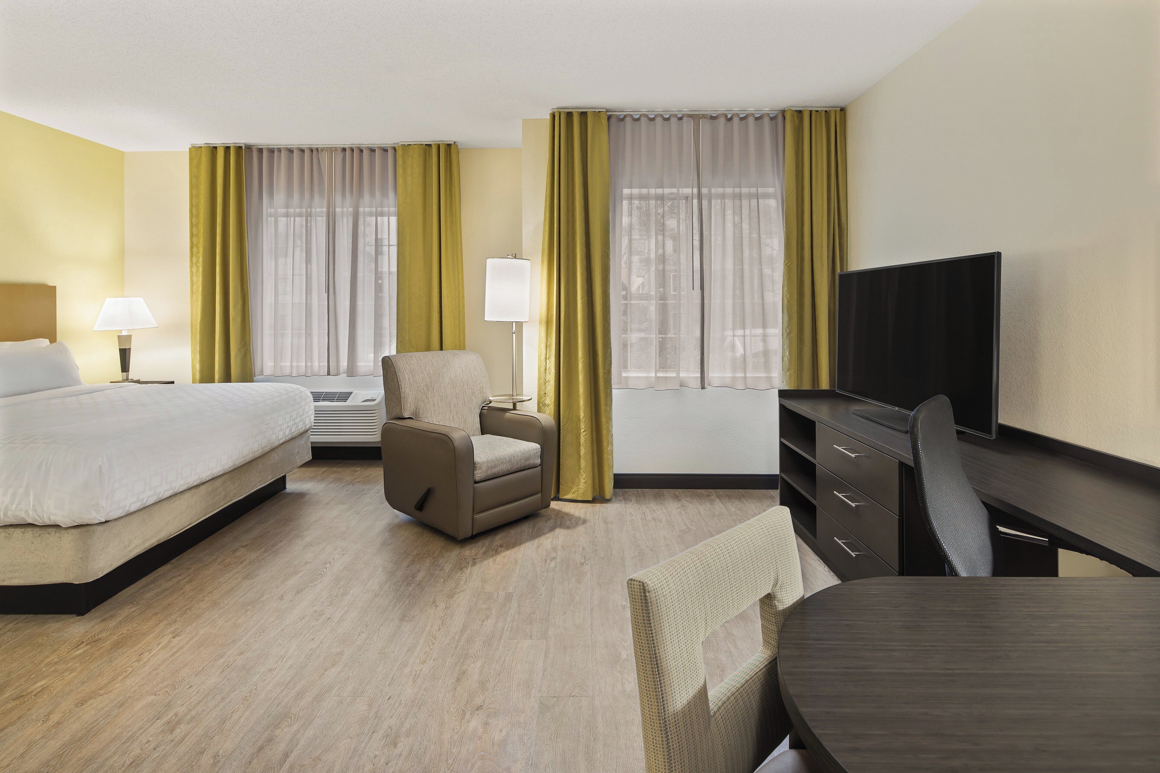Ein Hotelzimmer mit einem Bett, einem Schlafsofa, einem Fernseher, einem Schreibtisch und einem Sessel.