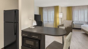 Une chambre d’hôtel équipée d’une kitchenette, d’un lit, d’un bureau, d’une chaise et d’un canapé.