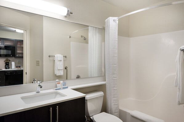 Baño con lavamanos, espejo, inodoro y cortina de ducha.