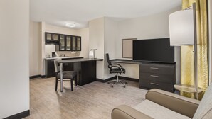 Une chambre d’hôtel compacte comprenant un coin cuisine, un bureau avec une chaise, une télévision et un lit.