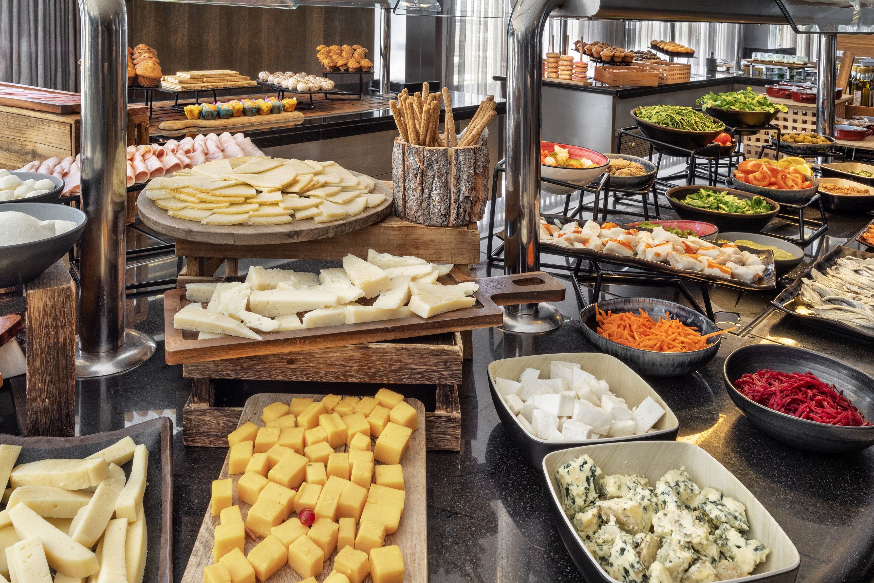 A buffet with various food items including cheeses, meats, and vegetables.
