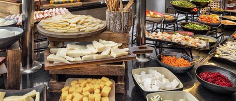 A buffet with various food items including cheeses, meats, and vegetables.
