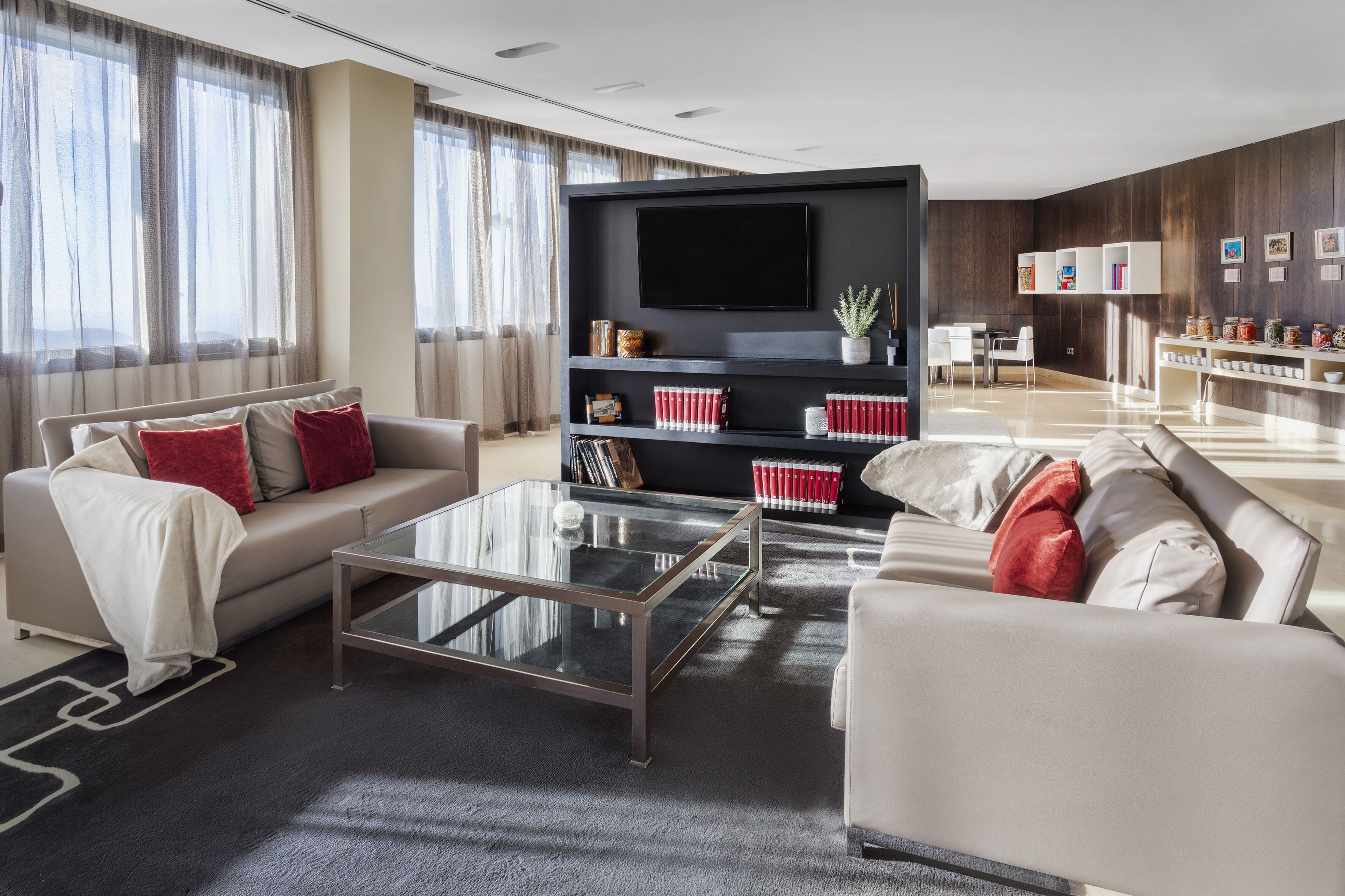 A modern living room with a sofa, coffee table, and a TV mounted on a wooden wall.