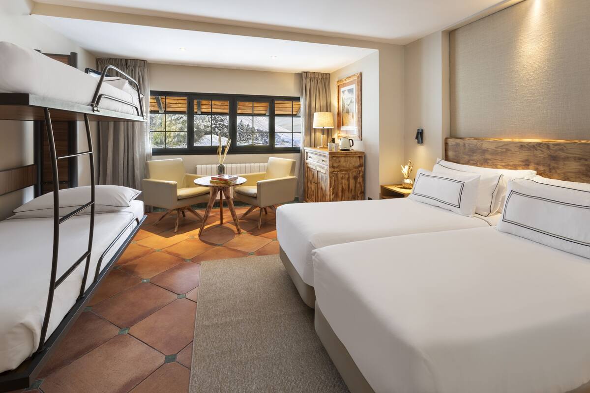 Habitación de hotel con literas, un sofá, una mesita redonda y vistas al exterior.