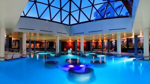 A large indoor swimming pool with multiple lanes, surrounded by lounge areas and a high ceiling with a geometric design. - Melia Sol Y Nieve (Monachil)