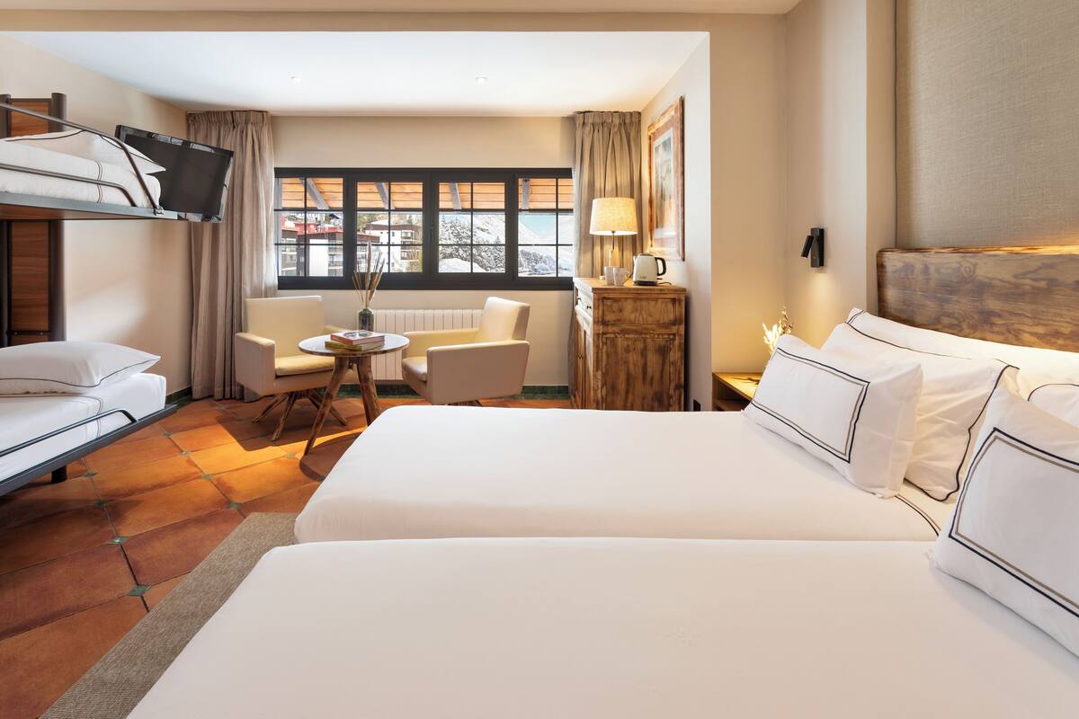Habitación de hotel con una cama grande, un escritorio, una silla, un sofá y una ventana con vistas.