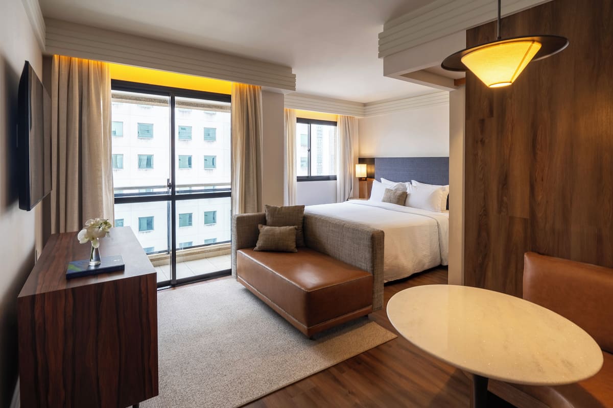 Una habitación de hotel con una cama, un sofá, un escritorio y una mesa.