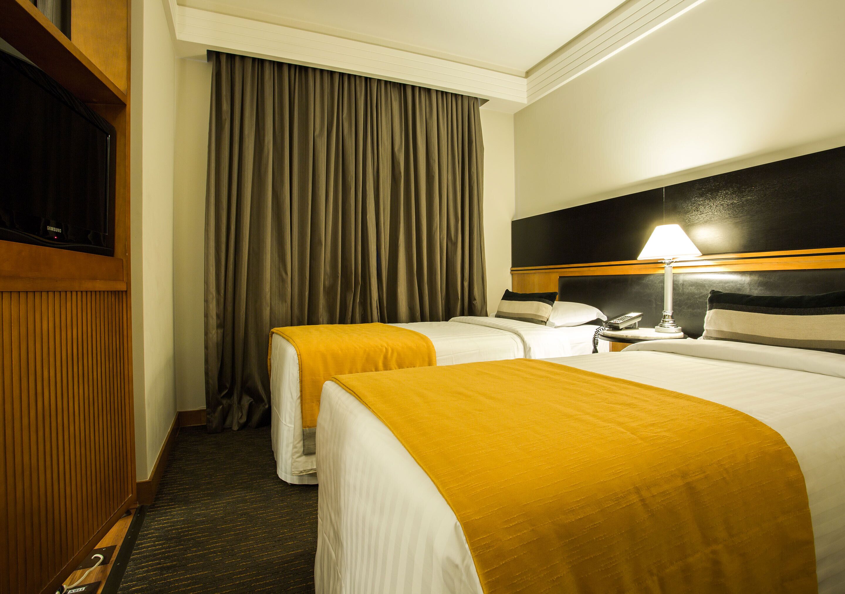 Una habitación de hotel con dos camas, un televisor, una lámpara y una mesita de noche.