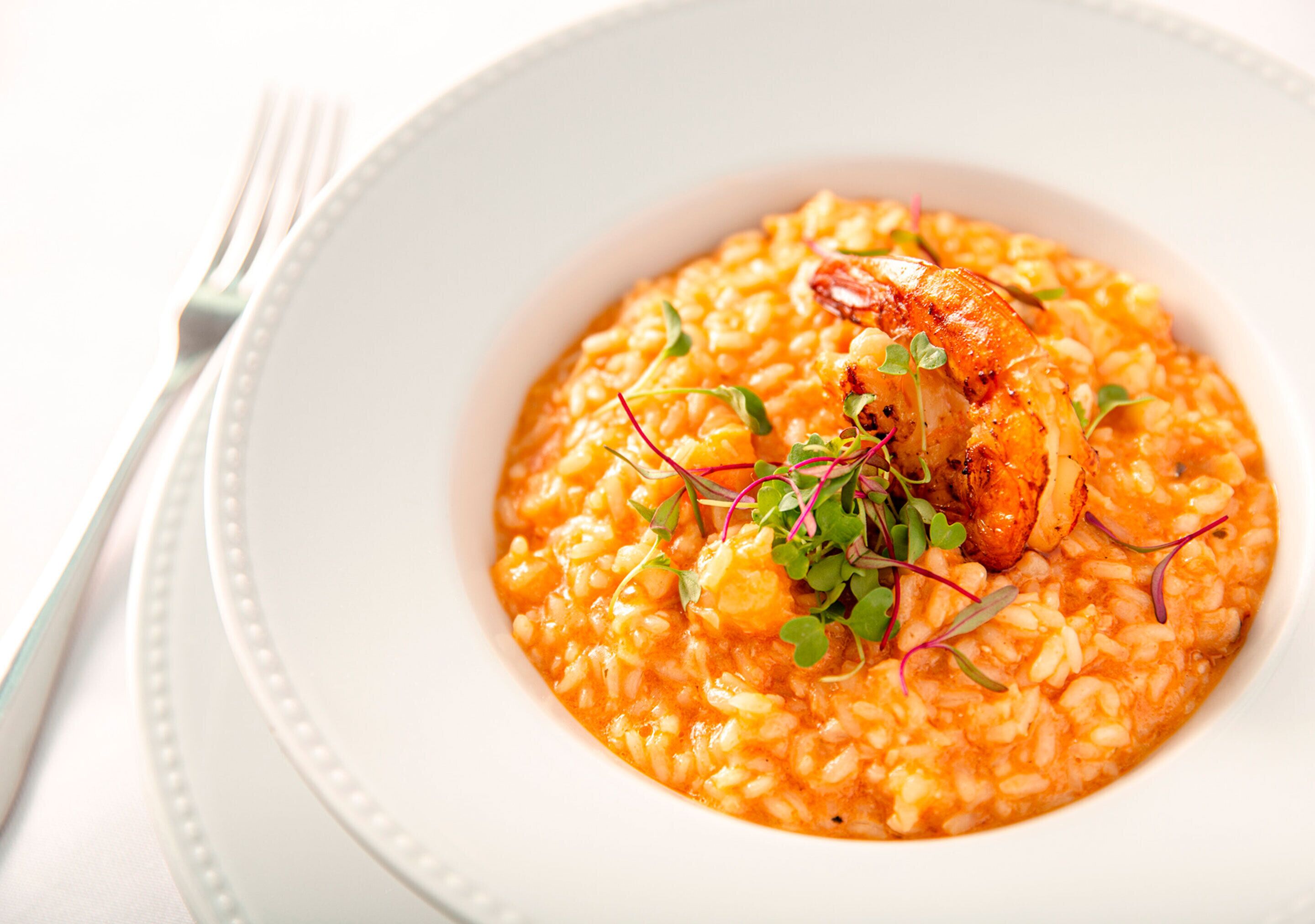 Uma tigela de risoto com camarões e guarnições.