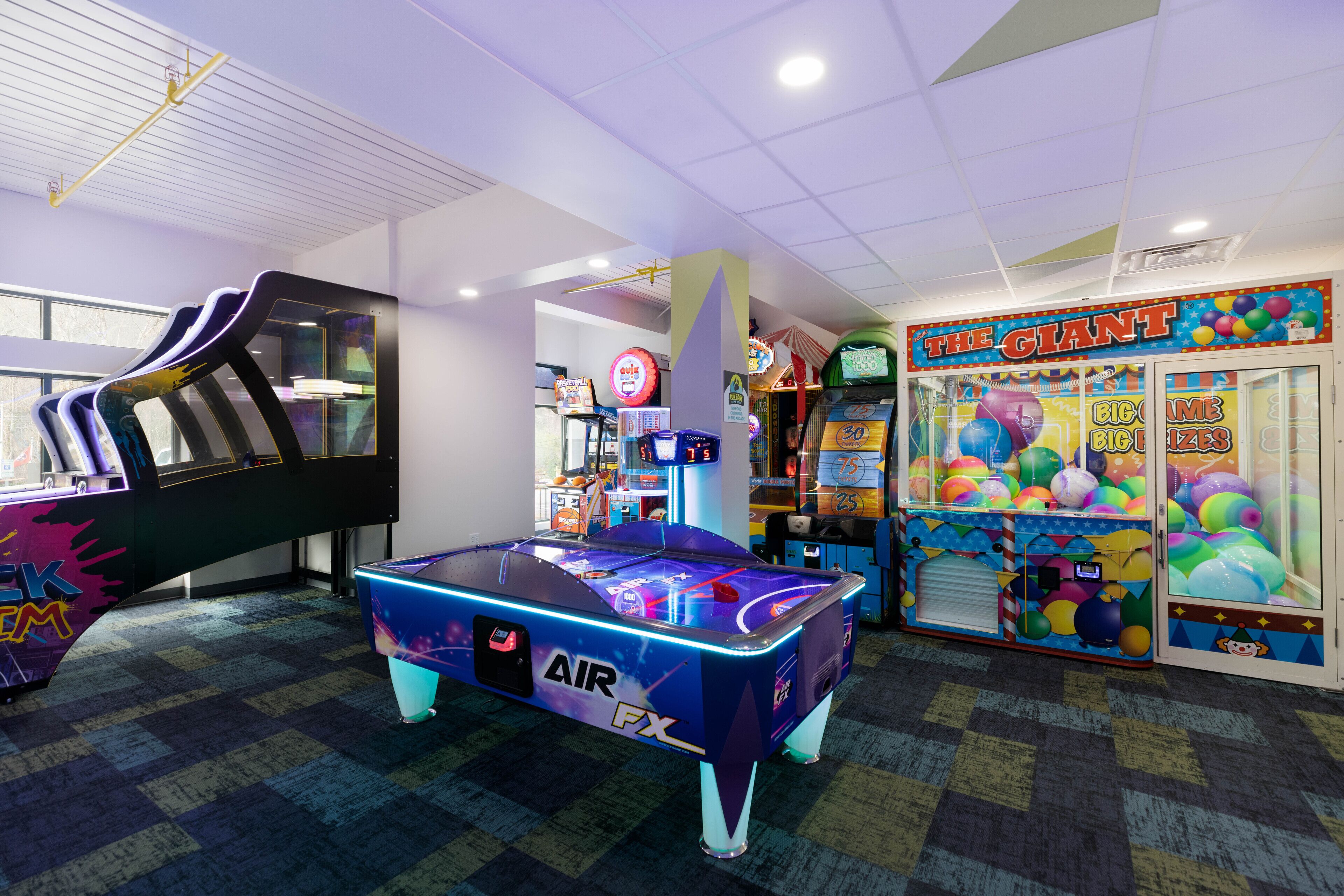 A brightly lit indoor space with a pool table, arcade games, and a claw machine.