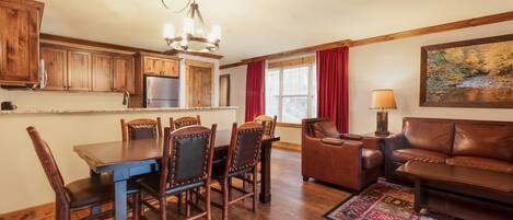 A spacious kitchen with wooden cabinets, a dining table with chairs, a leather sofa, and a rug.