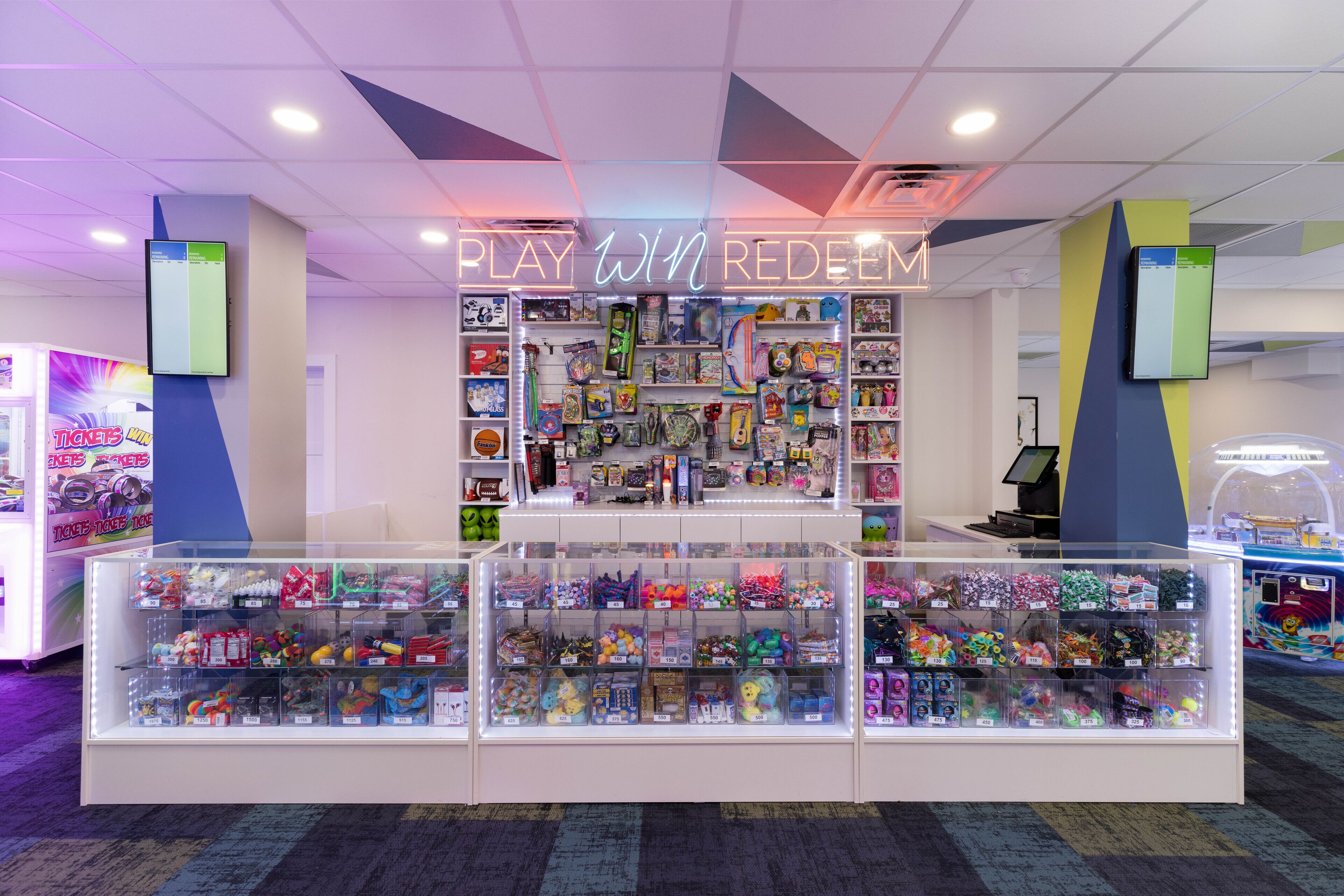 Un magasin bien éclairé, avec une enseigne au néon sur laquelle on peut lire « JOUER, GAGNER, UTILISER », et des étagères remplies de jouets et de jeux.