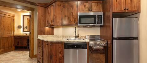 A kitchen with wooden cabinets, stainless steel appliances, and a granite countertop.