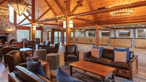 A spacious lobby with leather sofas, wooden tables, and a stone fireplace.