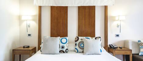 Habitación de hotel con una cama grande, dos mesitas de noche, una lámpara y un cabecero de madera.