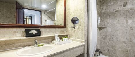 A bathroom with a marble sink, a mirror, a shower, and a towel rack.