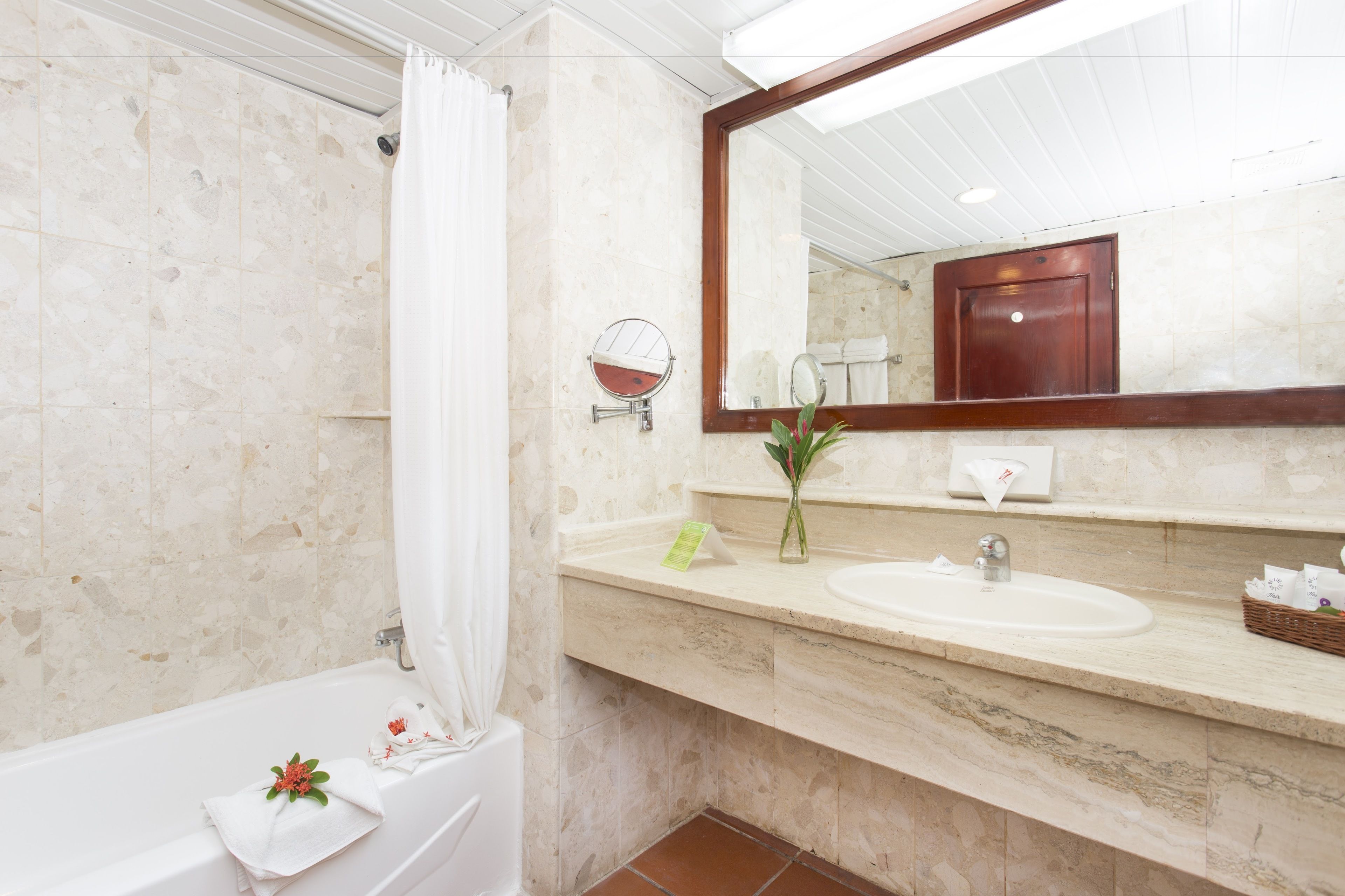 A bathroom with a bathtub, a sink, a mirror, and a shower curtain.