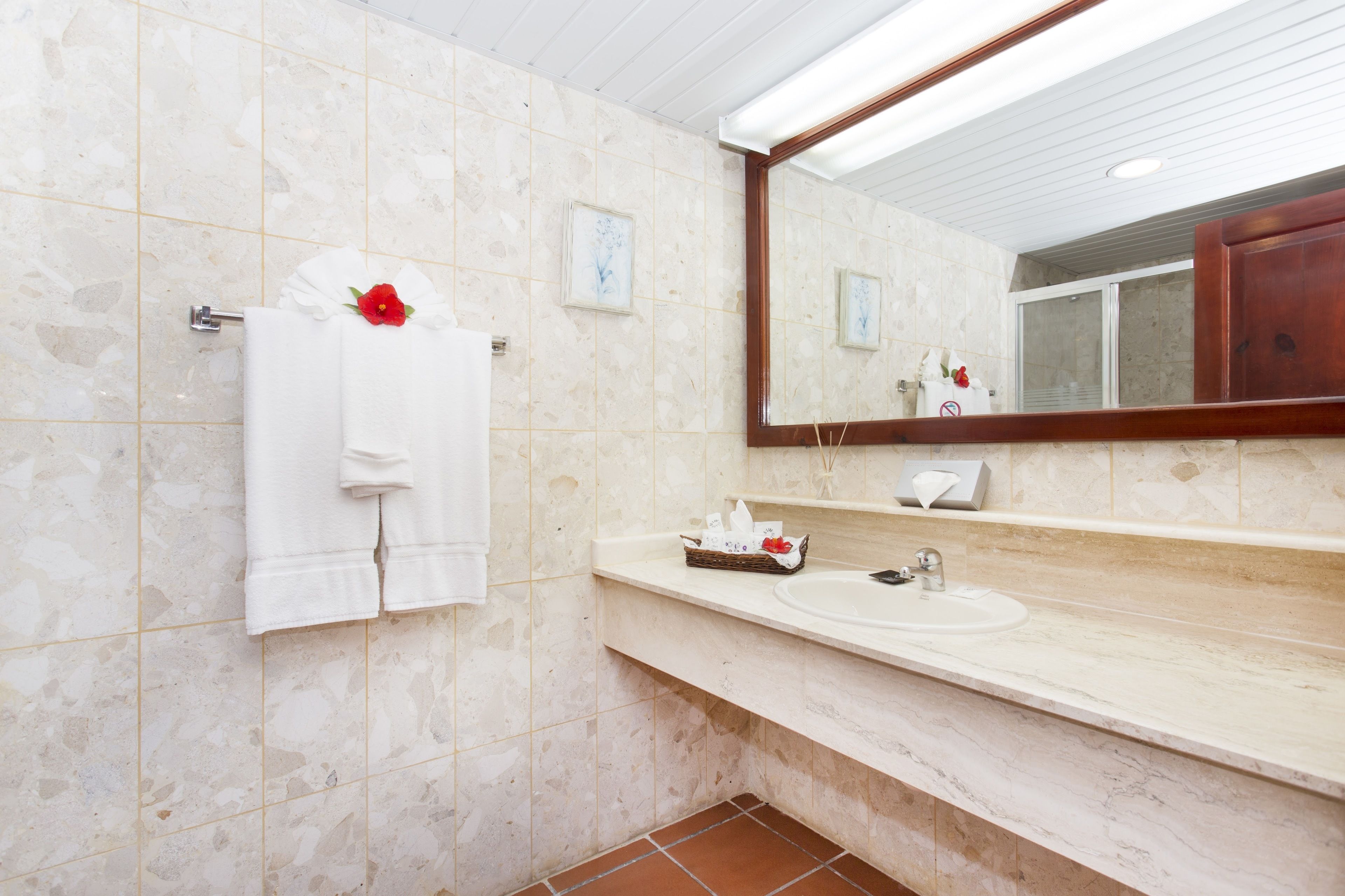 A bathroom with a marble-tiled wall, a white sink, and a mirror above it.