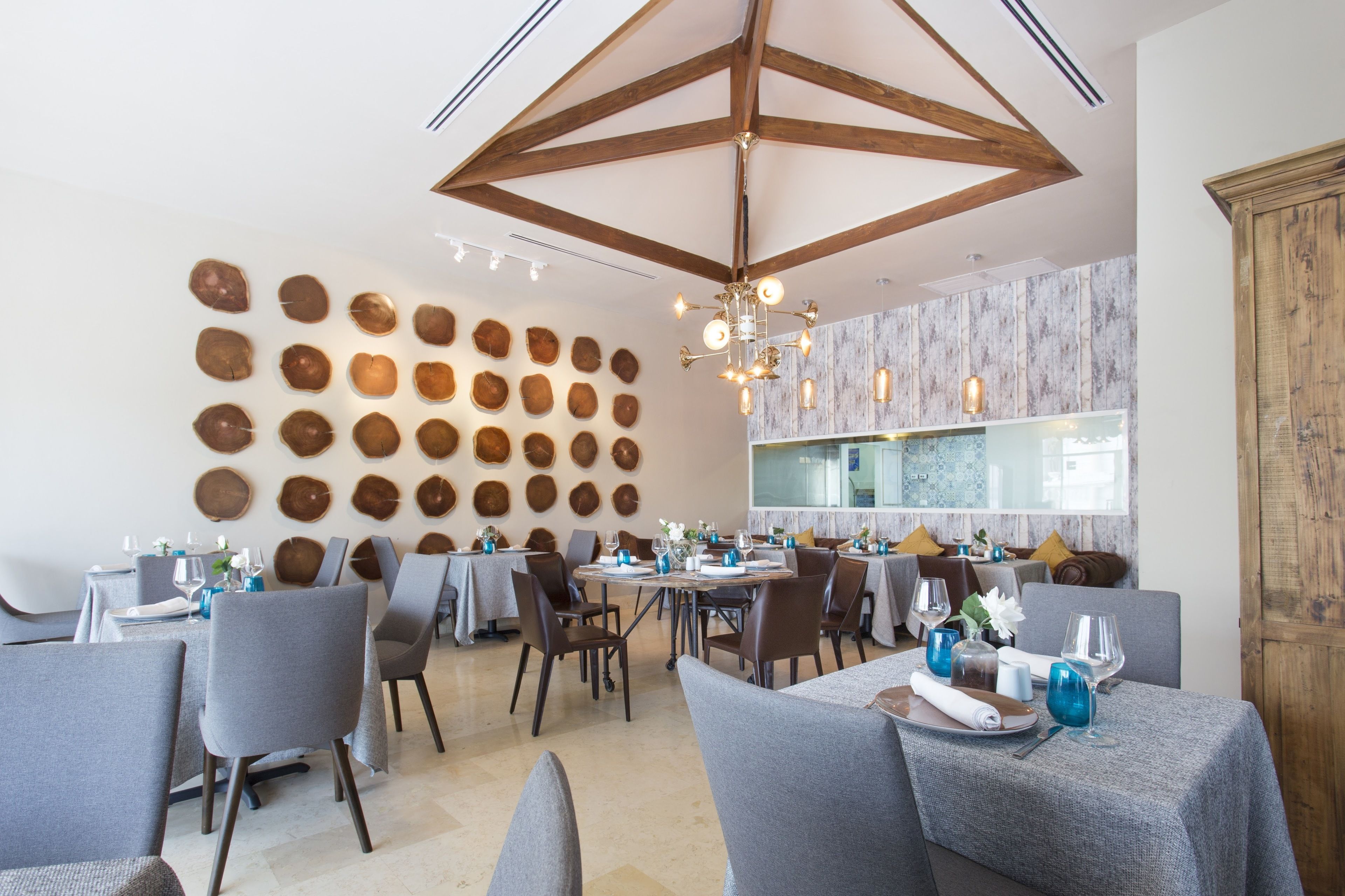 A dining area with round wooden wall decor, a chandelier, and tables set for dining.