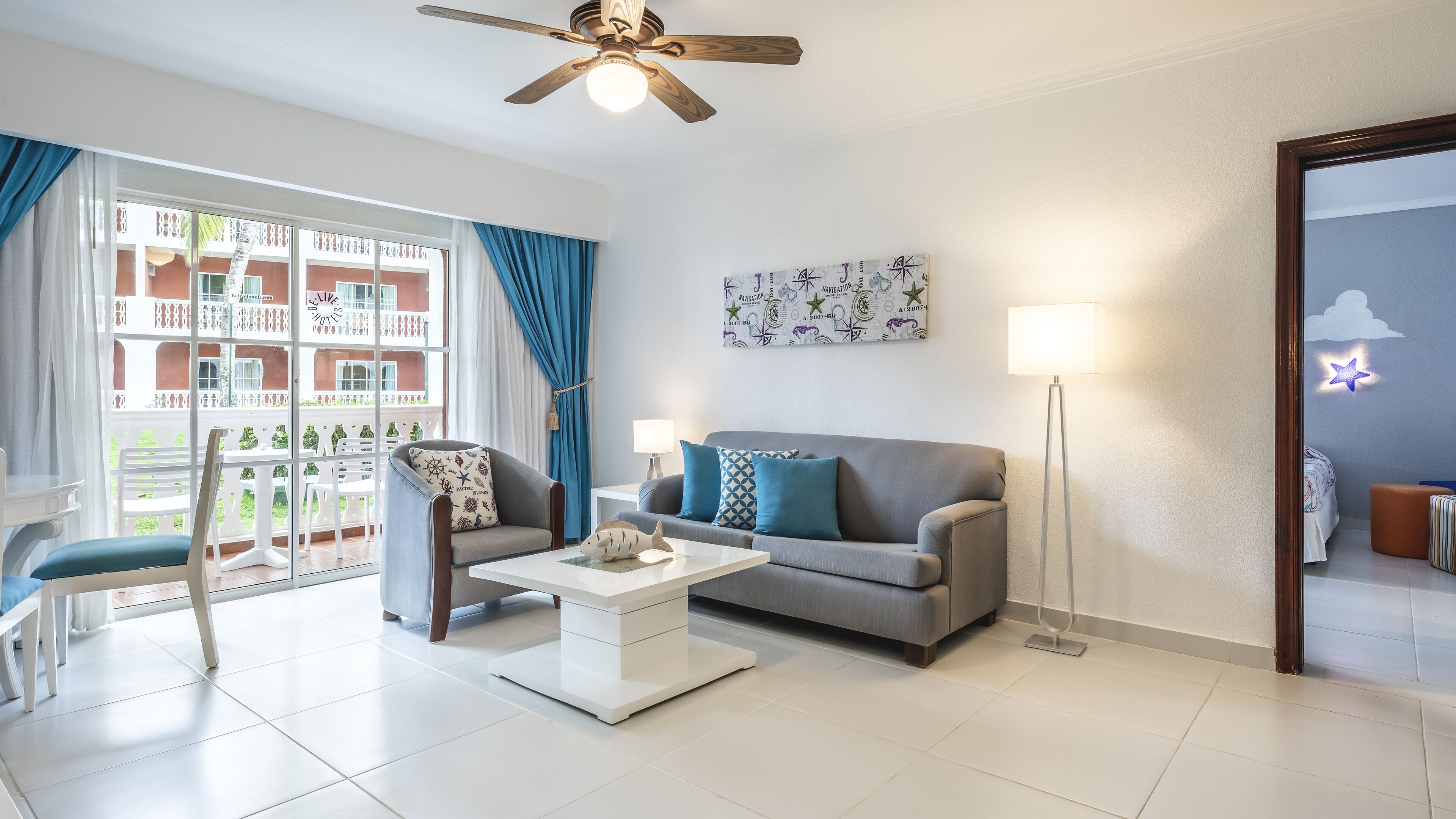 A modern living room with a grey sofa, a white coffee table, and a ceiling fan.