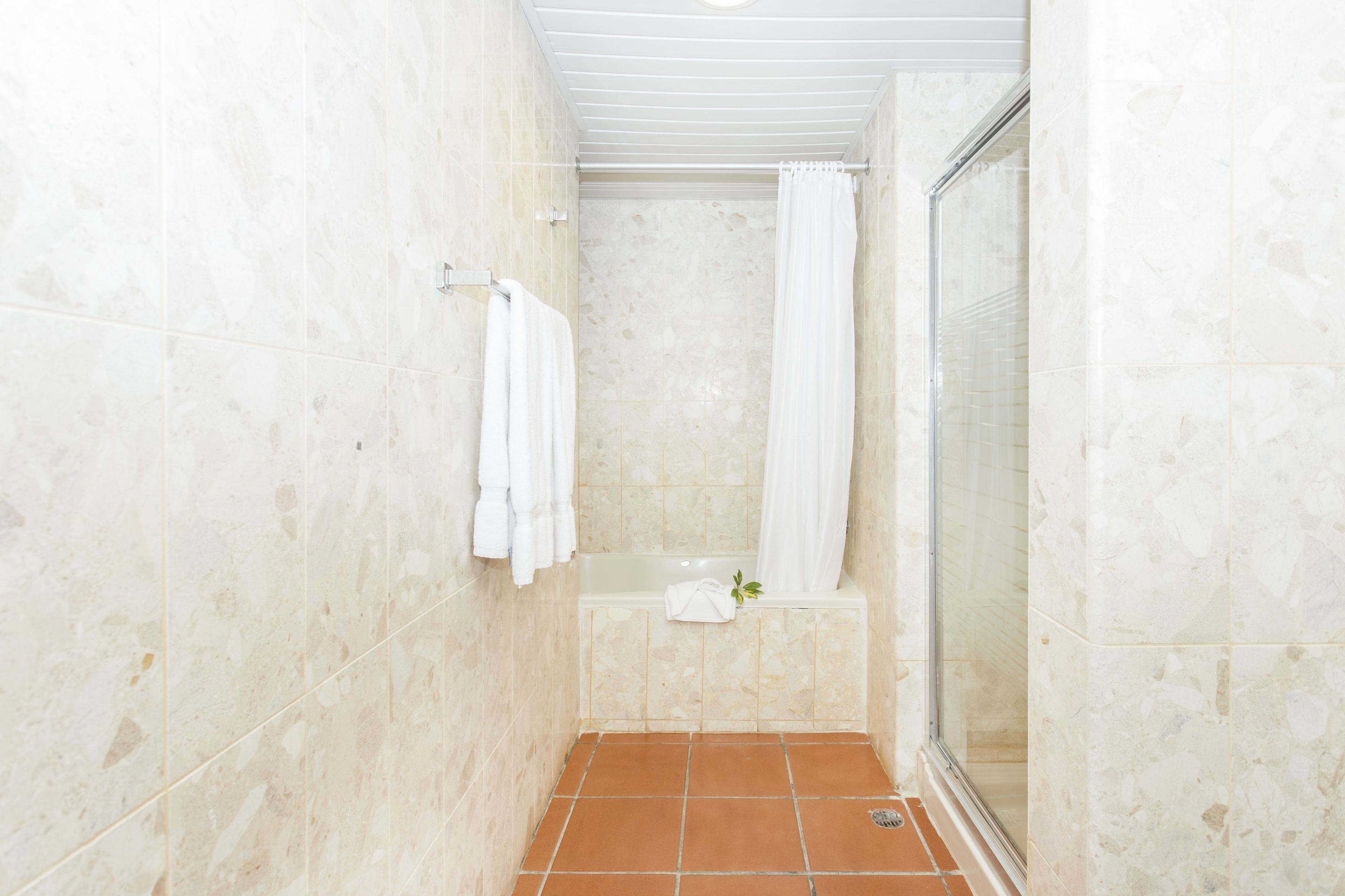 A bathroom with a shower, a bathtub, and a glass-enclosed shower stall.
