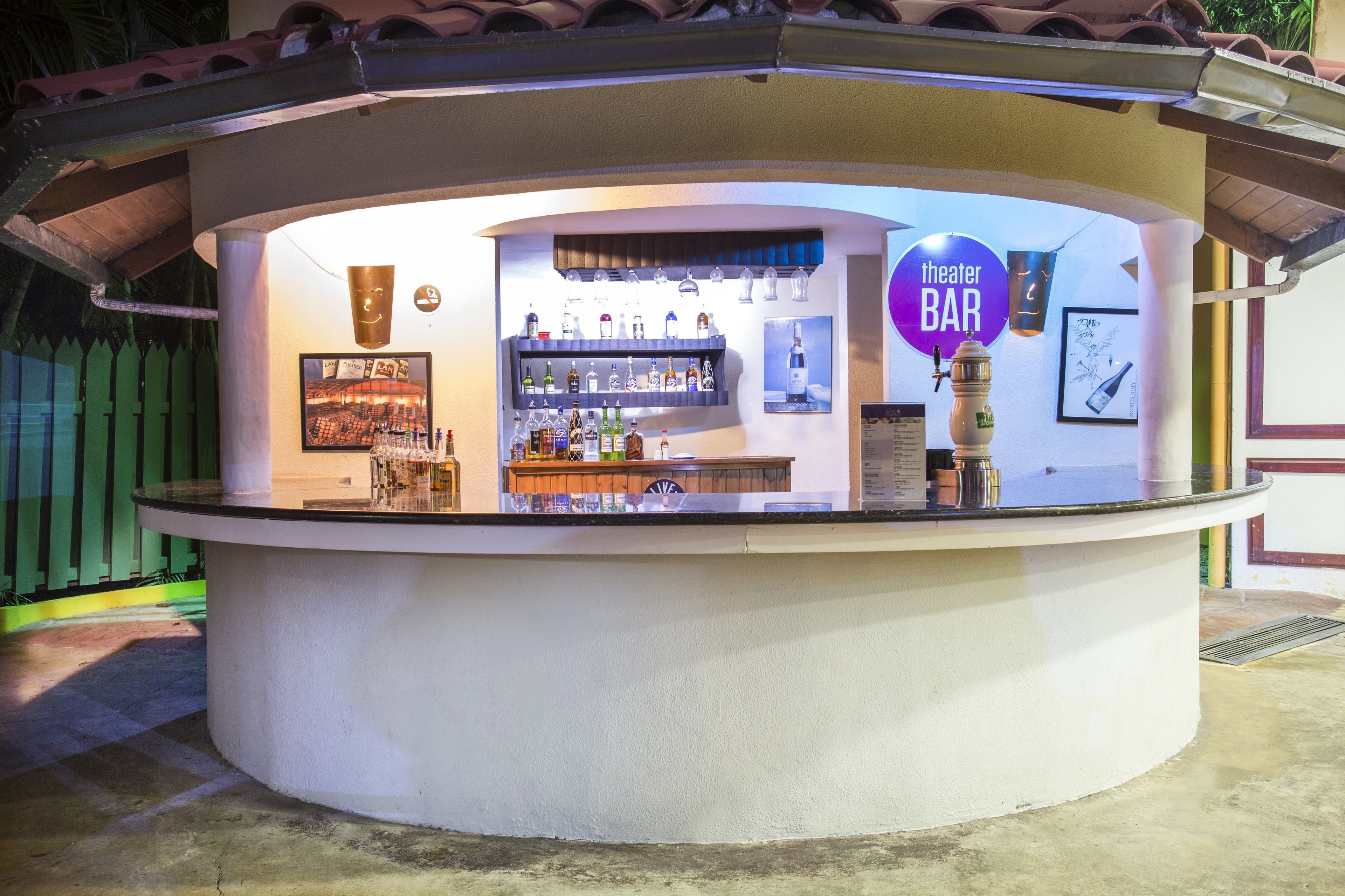 A bar with a circular counter, shelves with bottles, and a sign that reads "theater BAR".