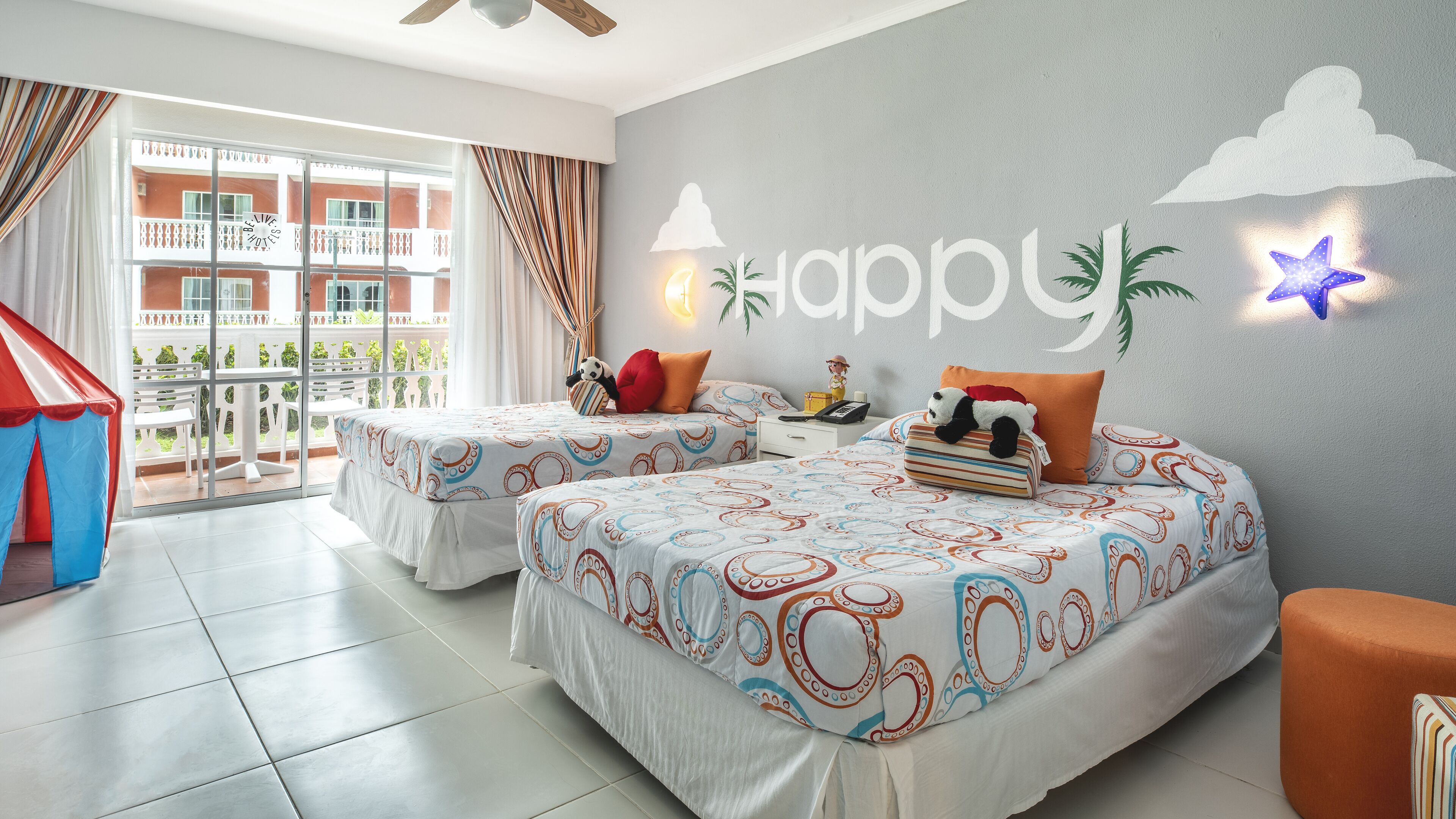 A hotel room with two beds, a balcony, and a view of the building.