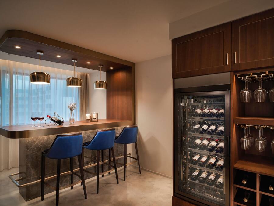 A modern kitchen with a bar area, wine refrigerator, and bar stools.