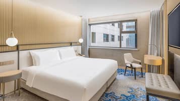 A hotel room with a large bed, a desk, a chair, and a TV.