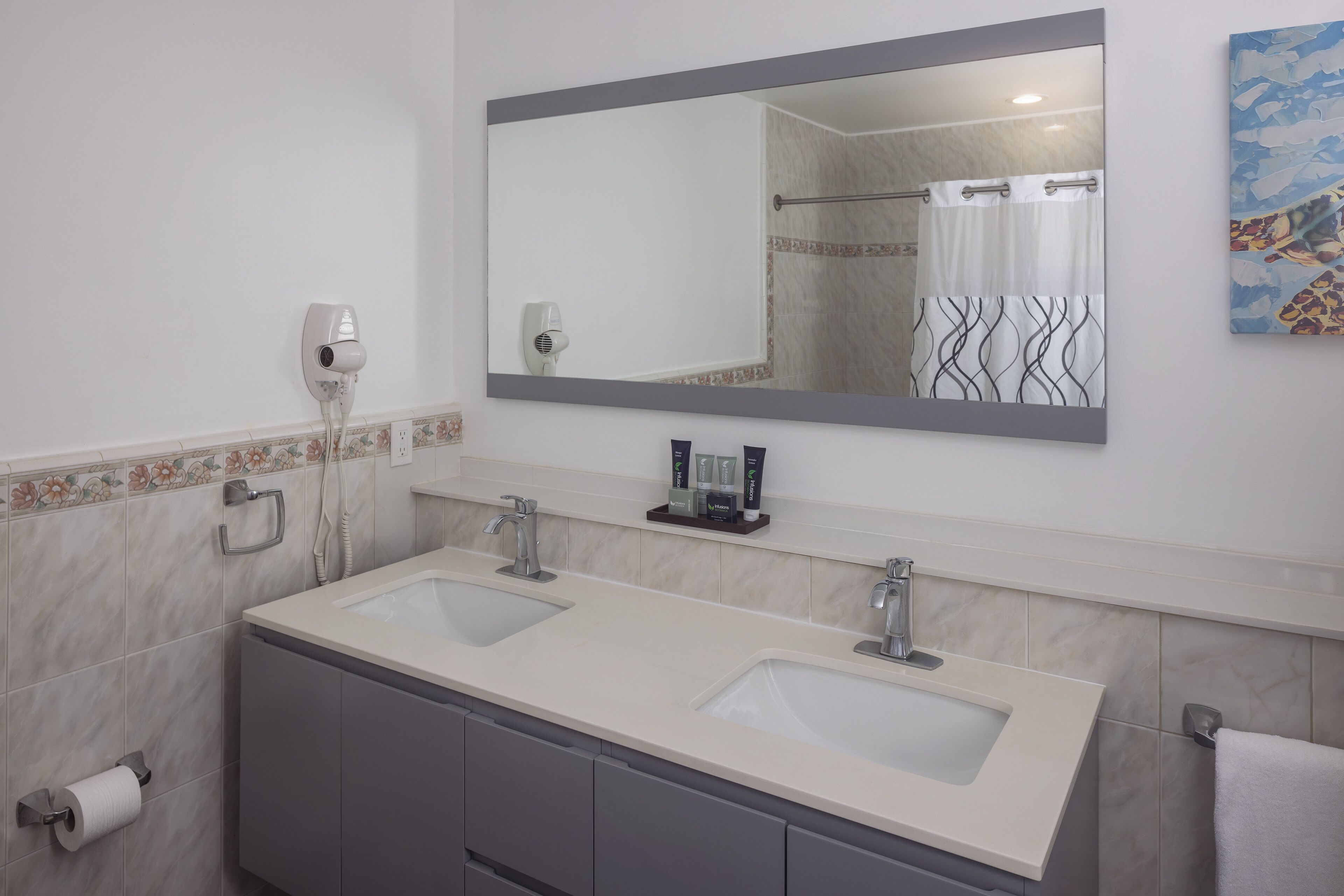 A bathroom with two sinks, a mirror, a towel rack, and a shower curtain.