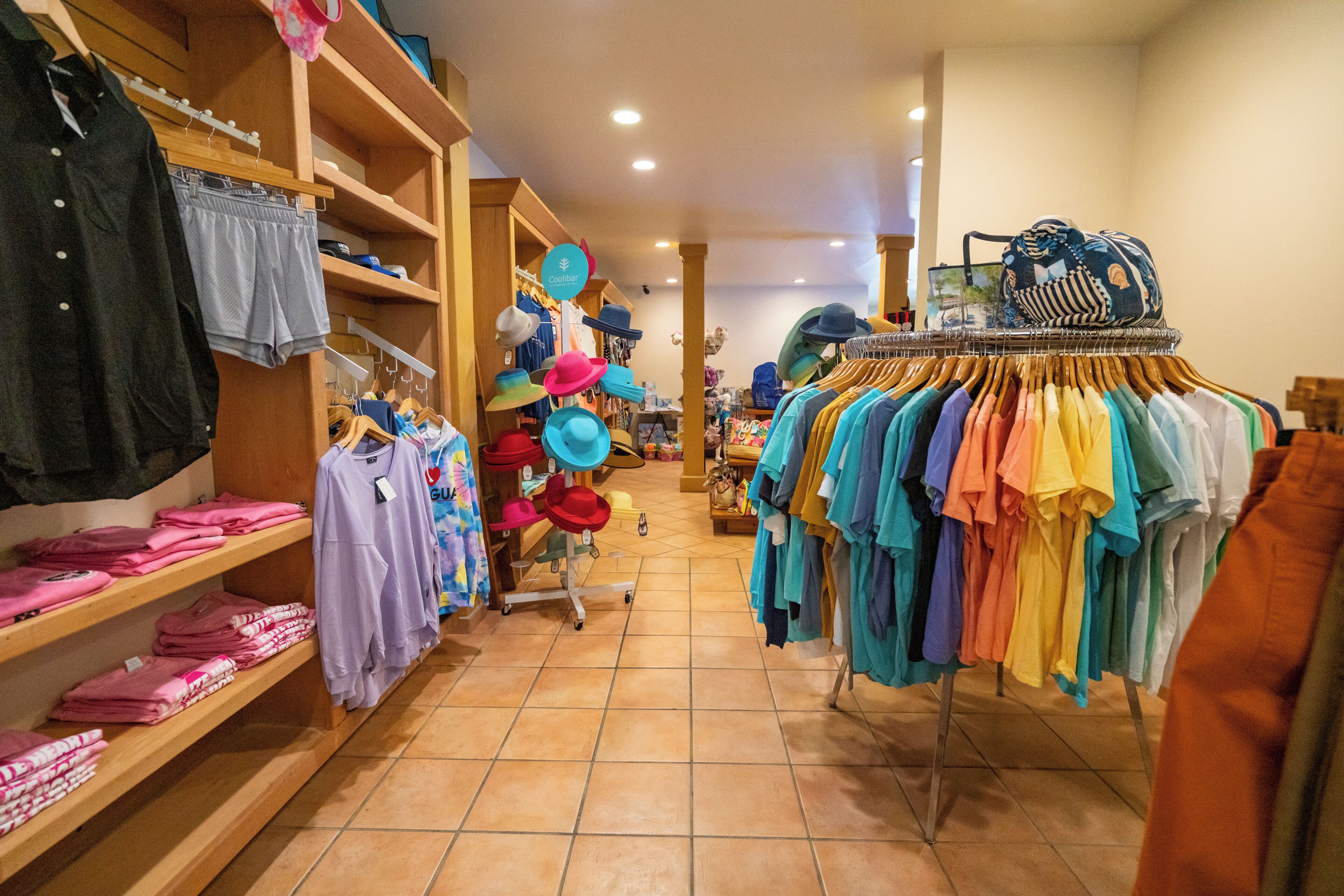 A clothing store with racks of colorful shirts and hats.