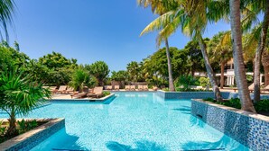 A clear blue pool surrounded by lounge chairs and palm trees, with a tiled edge and steps leading into the water. - Zoetry Curaçao Resort & Spa - All Inclusive (Willemstad)