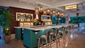 A bar area with a sign reading "FLORA LOBBY BAR", wicker hanging lights, bar stools, and a large potted plant. - Zoetry Curaçao Resort & Spa - All Inclusive (Willemstad)