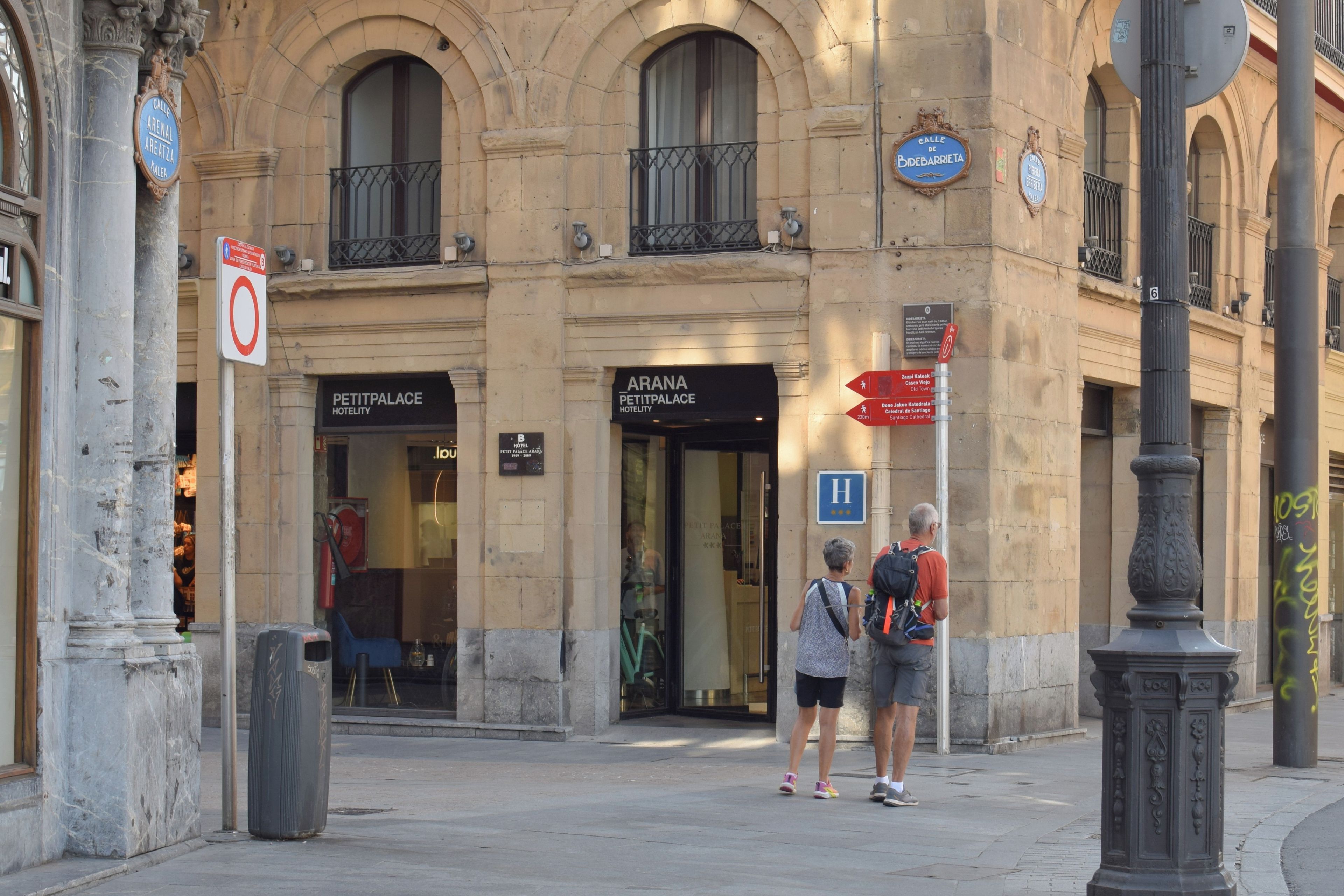 A historic building with 'ARONA PETIT PALACE HOTEL' signage, a 'Calle de Bidebarrieta' street sign, and a 'H' for hospital nearby.