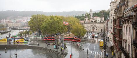 Una plaza urbana con tranvías, una bandera y edificios.