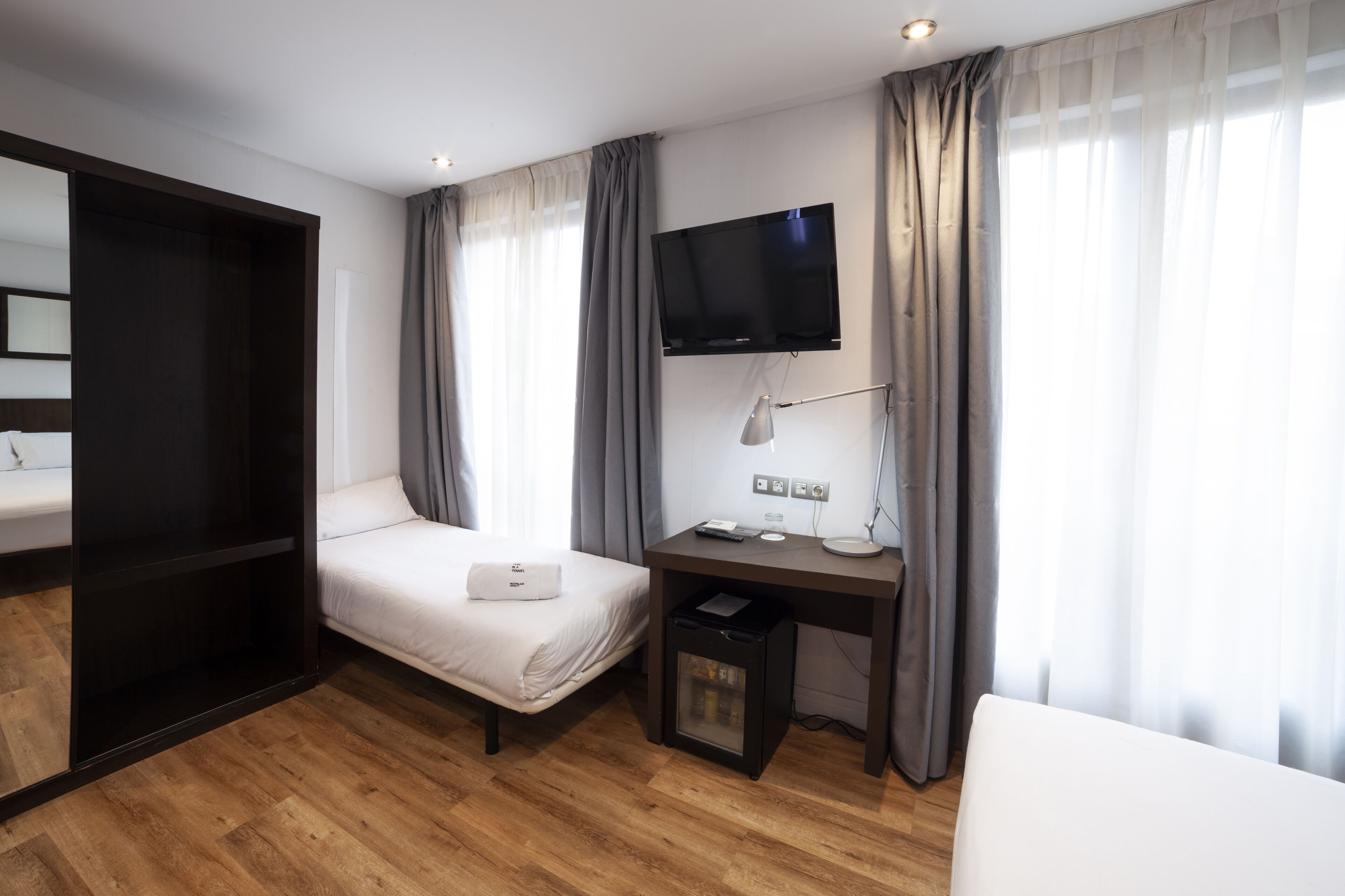Une chambre d’hôtel moderne équipée d’un lit, d’un bureau, d’une télévision et d’une armoire.
