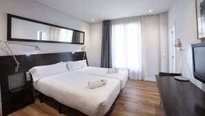 A hotel room with a large bed, bedside tables, a TV, and a mirror. - Petit Palace Arana (Bilbao)