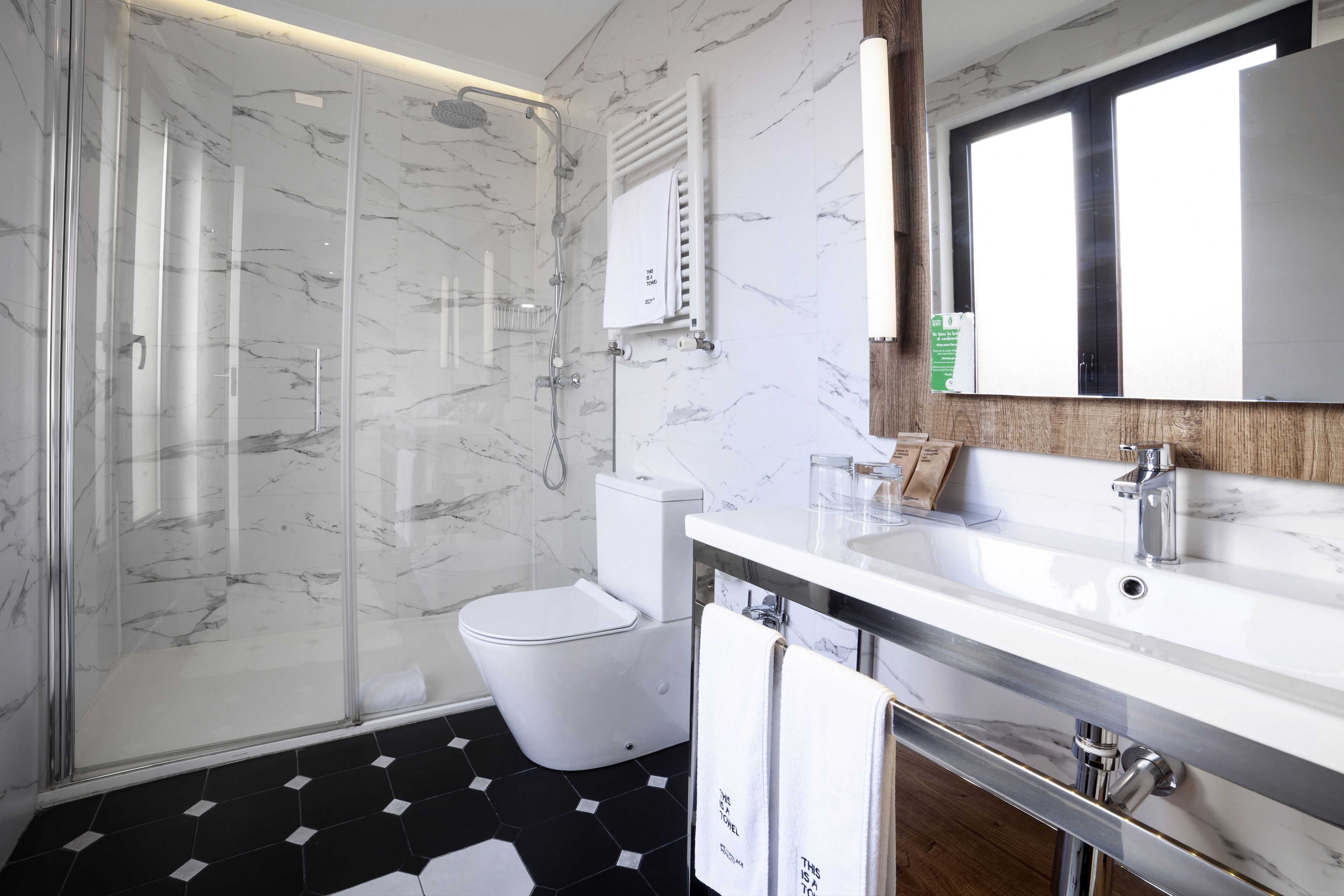 A modern bathroom with a glass-enclosed shower, a white toilet, and a marble-tiled floor.