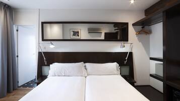 Una habitación de hotel moderna con una cama grande, lámparas de noche, un espejo y un armario.