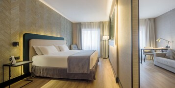 Una camera d'albergo con un letto grande, comodini, una scrivania e un divano.