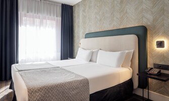 Ein Hotelzimmer mit einem großen Bett, einem Nachttisch mit Telefon und einer Wandlampe.