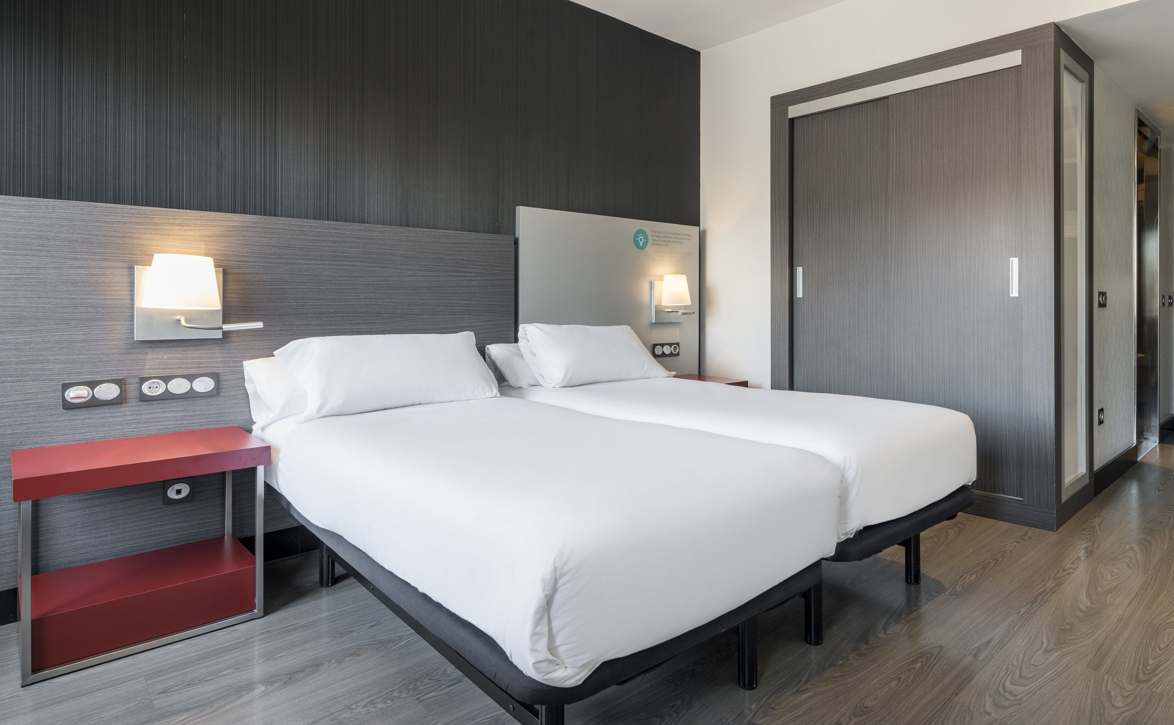 Una habitación de hotel con cama, mesitas de noche y un armario.