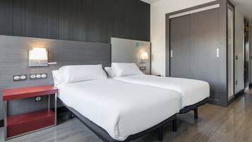 Una habitación de hotel con cama, mesitas de noche y un armario.